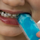 Child biting into blue freeze pop